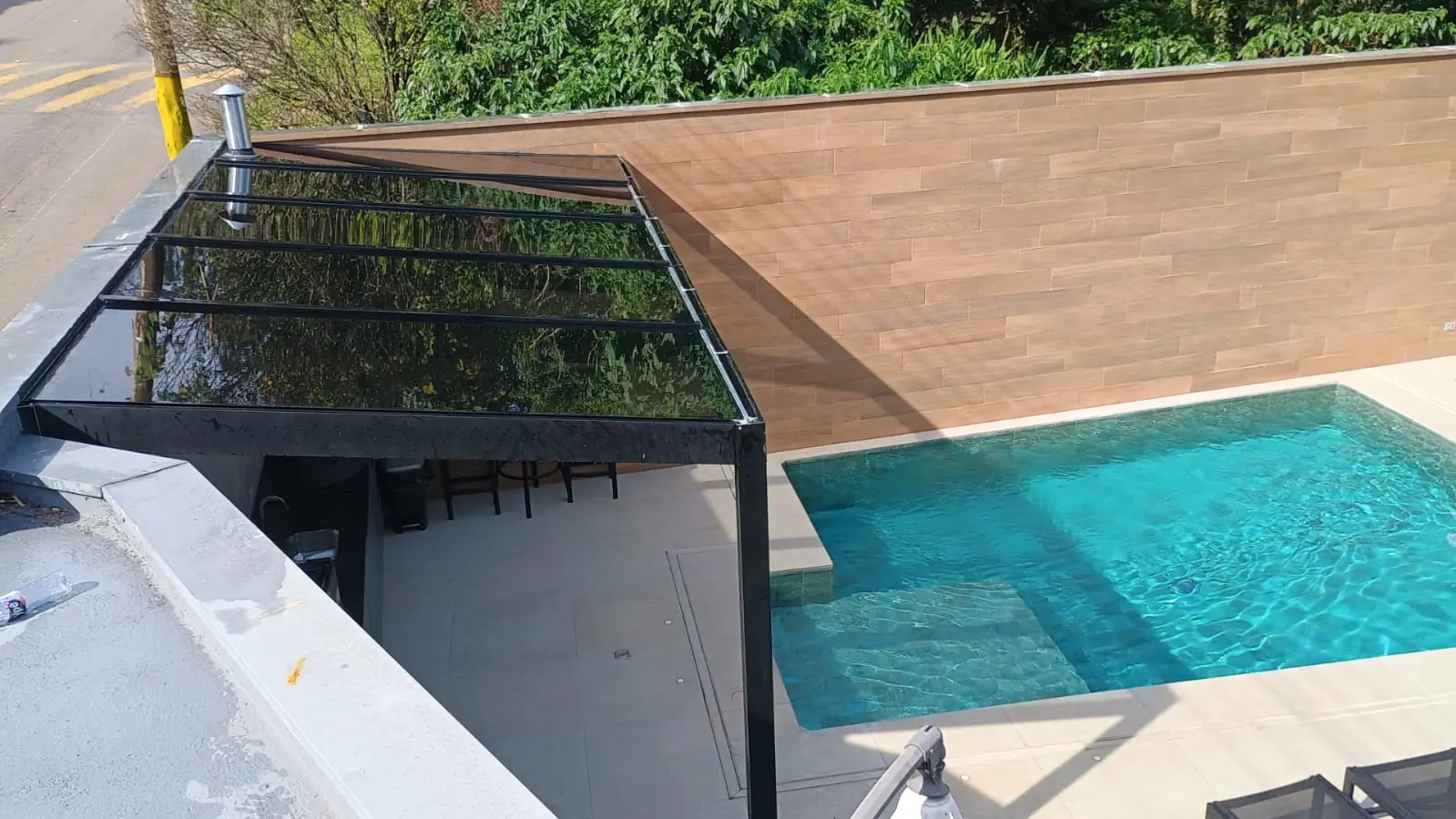 Cobertura de vidro temperado fumê instalada sobre o deck de uma piscina