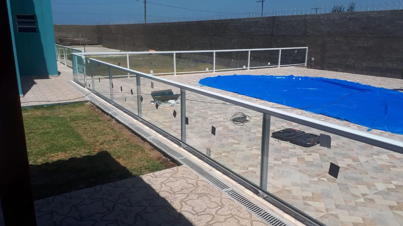 Guarda-corpo de vidro com prumos de aço inox contornando uma piscina