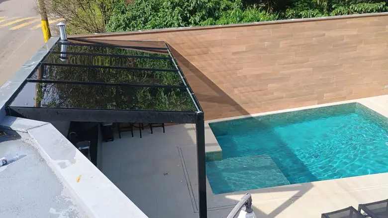 Cobertura de vidro temperado fumê instalada sobre o deck de uma piscina