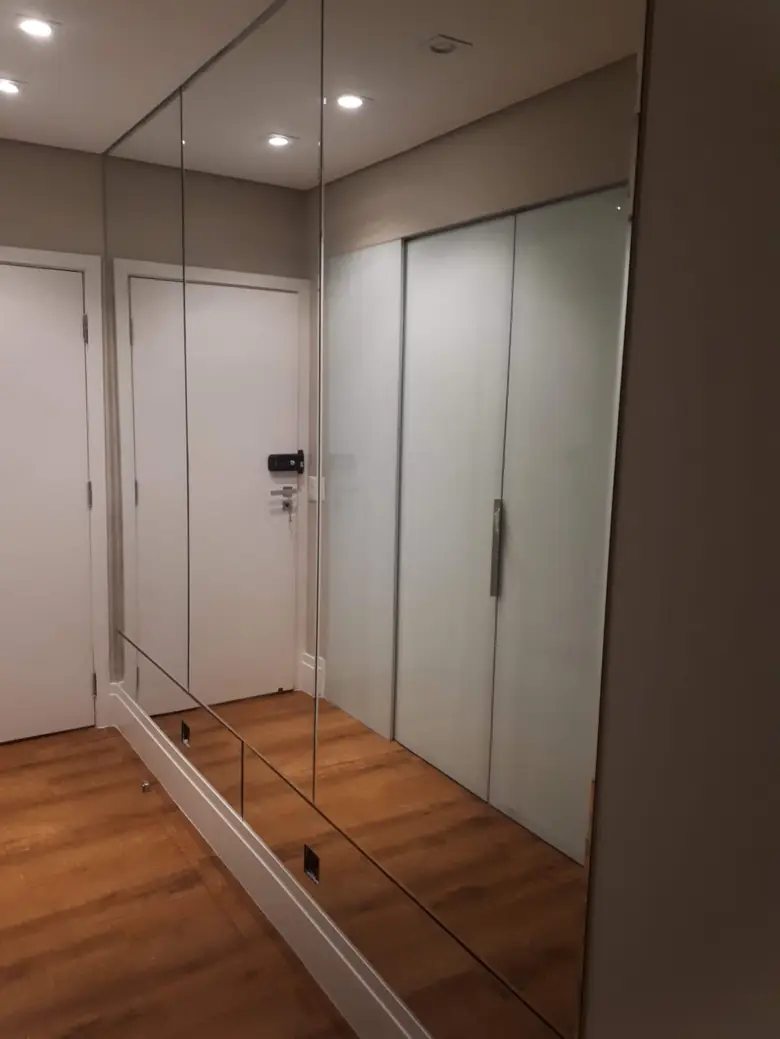 Espelho de parede inteira ampliando o corredor de acesso ao closet