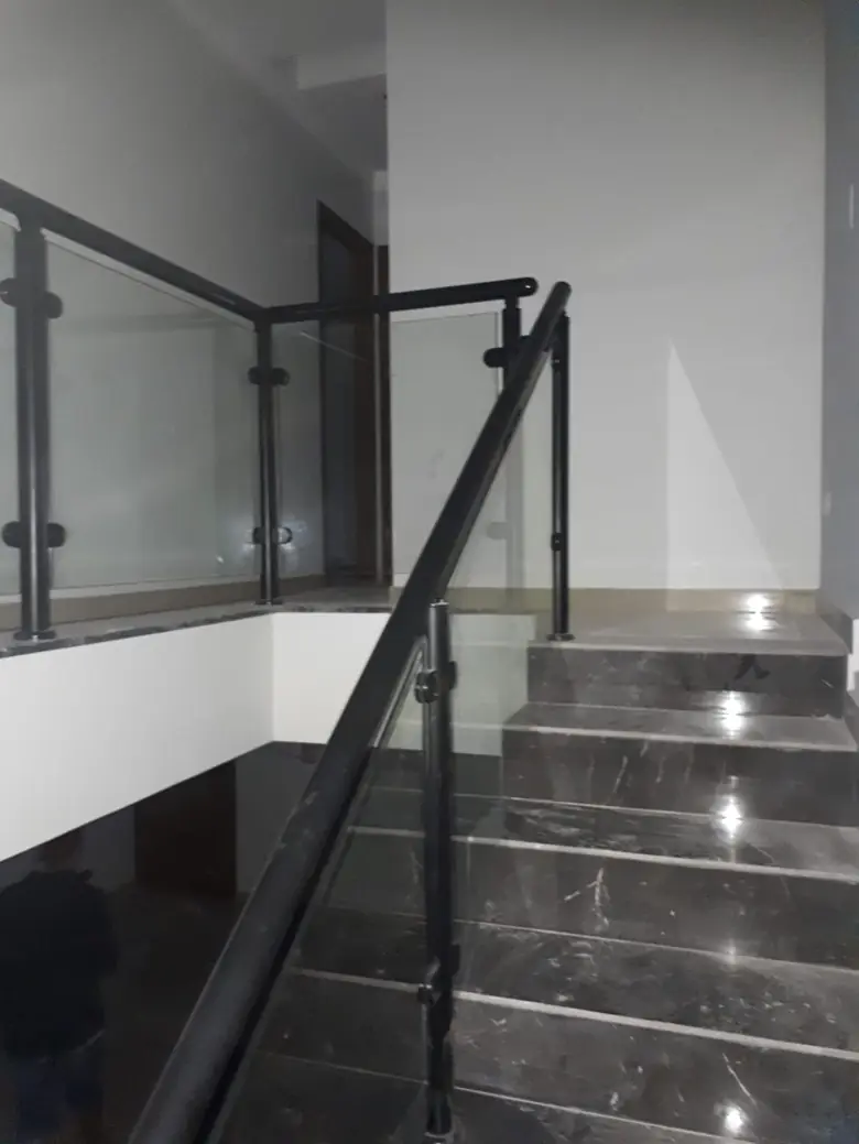 Escada com guarda-corpo de vidro e corrimão de ferro preto