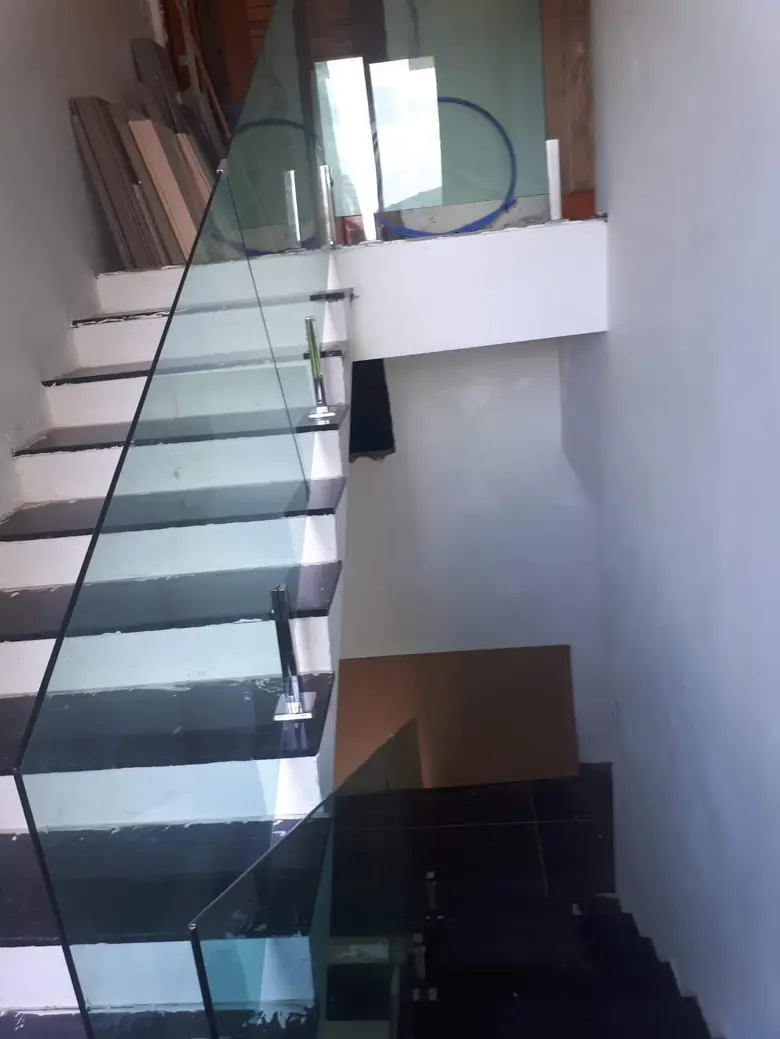Guarda-corpo de vidro acompanhando escada de mármore escuro