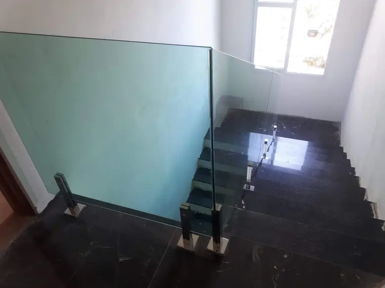 Guarda-corpo de vidro fechando o vão de uma escada de mármore
