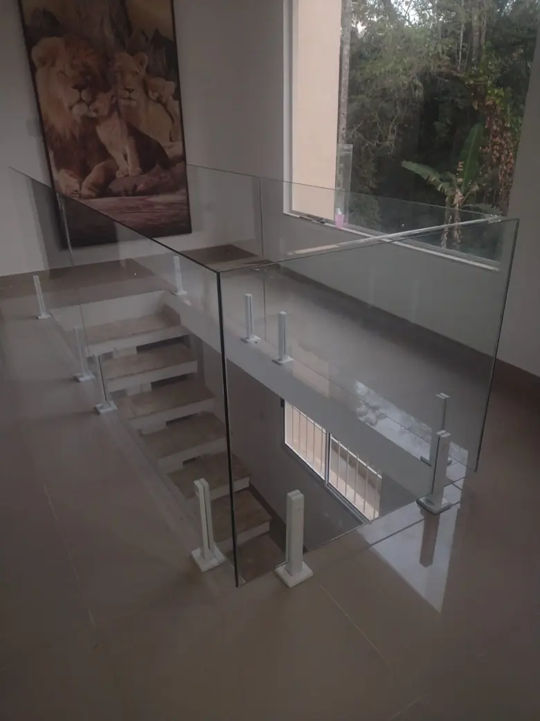 Guarda-corpo de vidro no mezanino de uma sala com pé-direito duplo