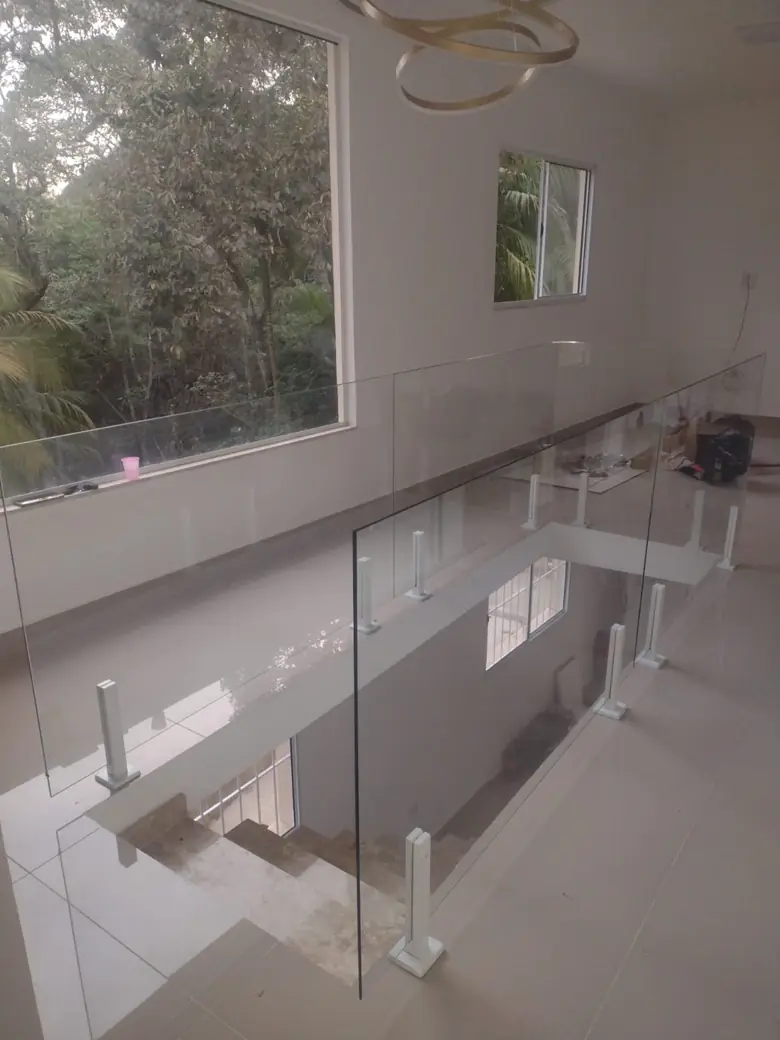 Guarda-corpo de vidro em mezanino de sala com janela ampla para a mata