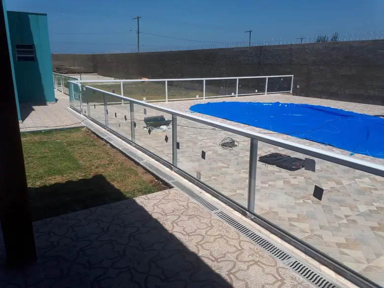 Guarda-corpo de vidro com prumos de aço inox contornando uma piscina