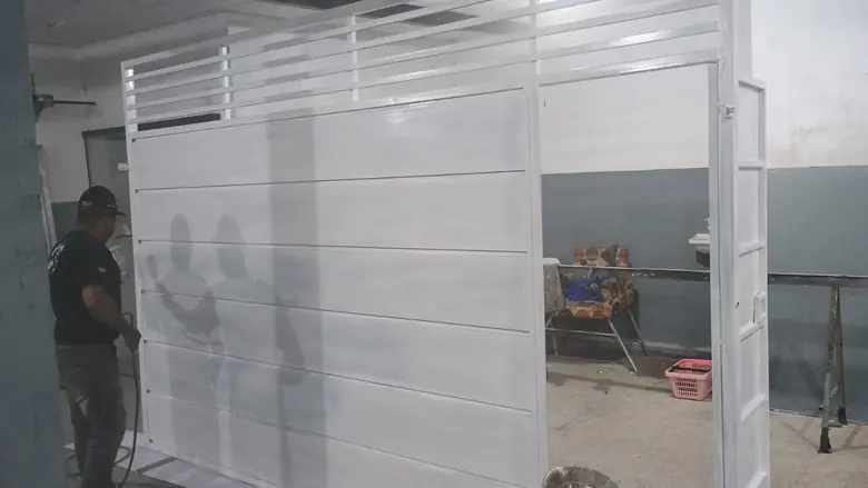 Portão basculante branco recebendo acabamento na oficina da Artfer